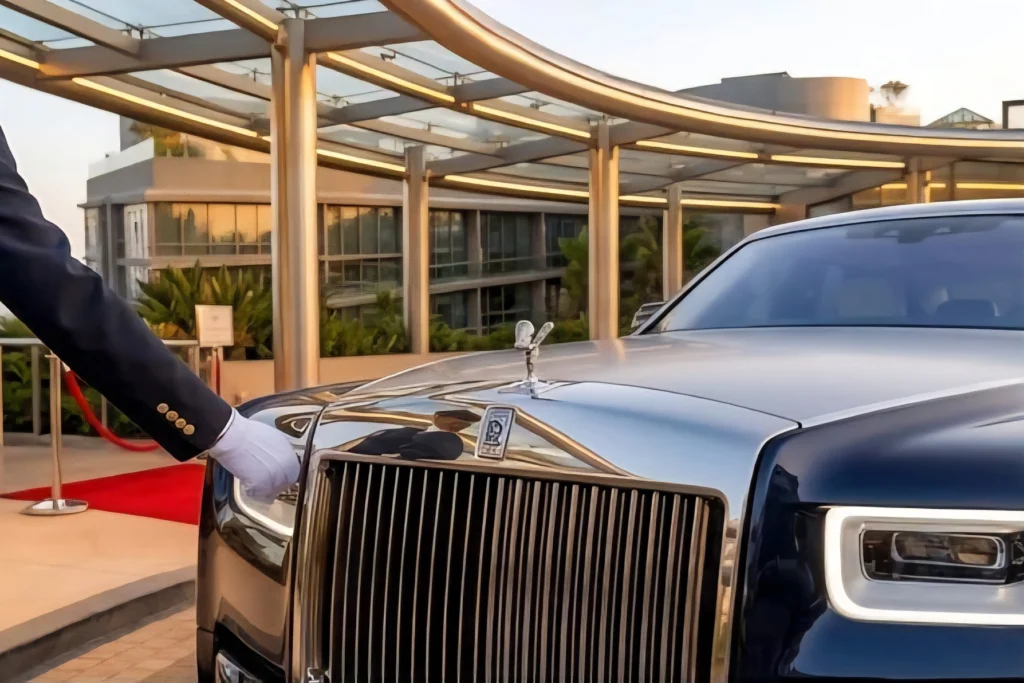 A doorman beside a Rolls-Royce under the glass arrival canopy